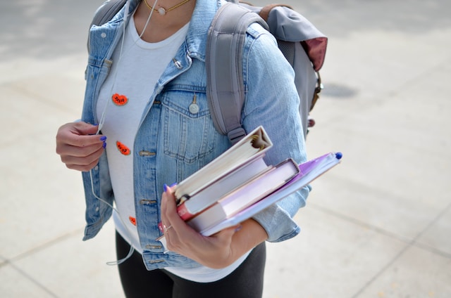 college student carrying books in her left hand