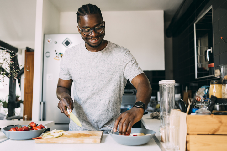 a man with glasses preparing breakfast while standing in the kitchen