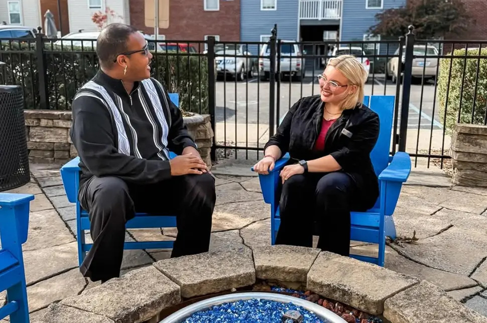 Two young adults sitting by a fire pit